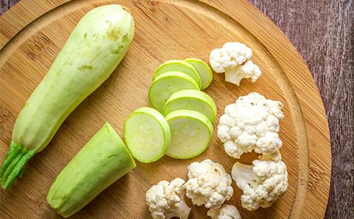 Tranches de courgettes et de chou-fleur sur une planche de bois