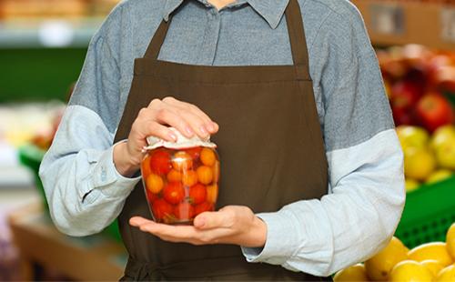 Femme tenant un pot de tomates en conserve