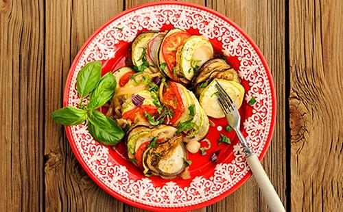 A dish on a plate of eggplant and tomatoes with herbs