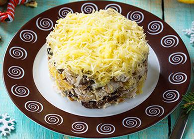 Puff salad on a plate with chicken, prunes, mayonnaise and grated cheese