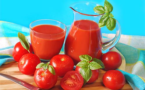 Tomatensap in een kruik en een glas, tomaten en kruiden