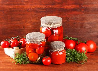 Pickled tomatoes in jars with herbs