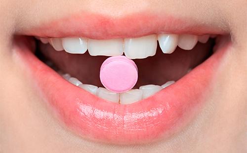 Tableta rosa en la boca
