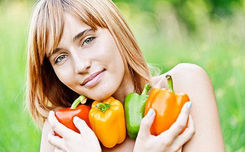 Beautiful girl with multi-colored peppers in hands