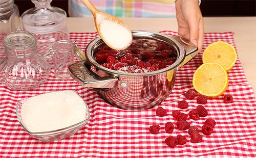 Mujer cocina mermelada de frambuesa