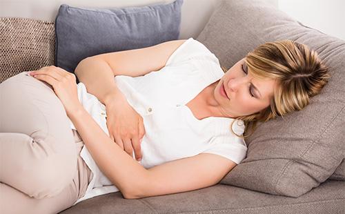 Chica tumbada en el sofá con dolor de estómago