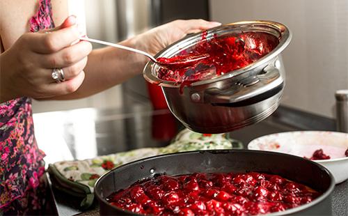 Woman is cooking cherry jam