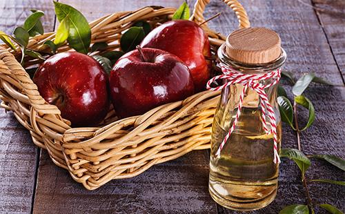 Apple cider vinegar and red apples in a basket