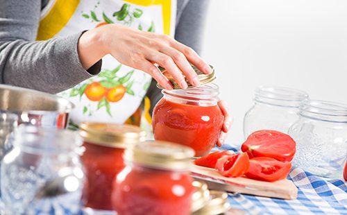 Mujer llena tarros con salsa de tomate
