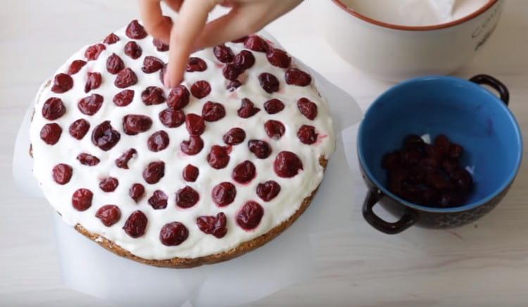 El primer pastel se engrasa con crema y se esparce uniformemente las cerezas.