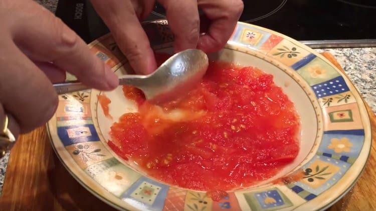 Amasar el tomate en escabeche con una cuchara.