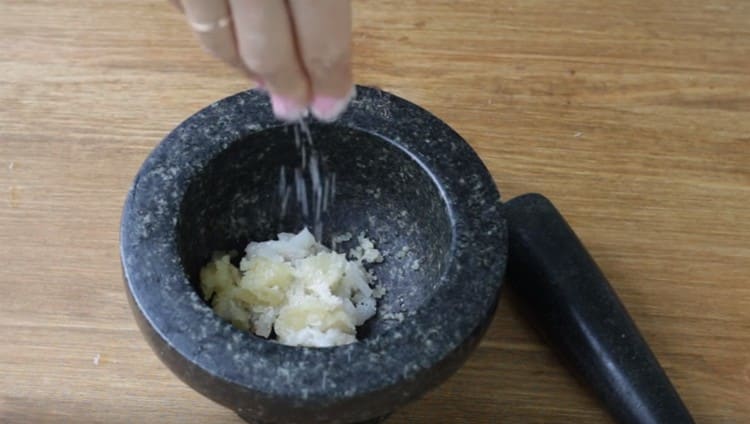 In a mortar, put chopped lard, garlic, salt.