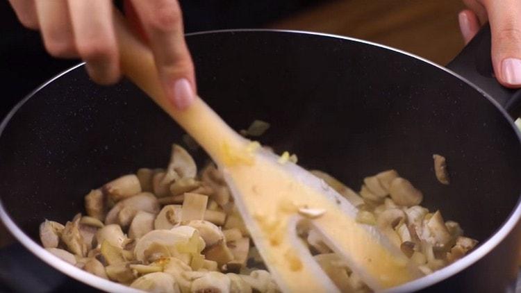 Agregue los champiñones a la cebolla, cocine a fuego lento.