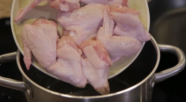 In the pan with water, lay the chicken wings.