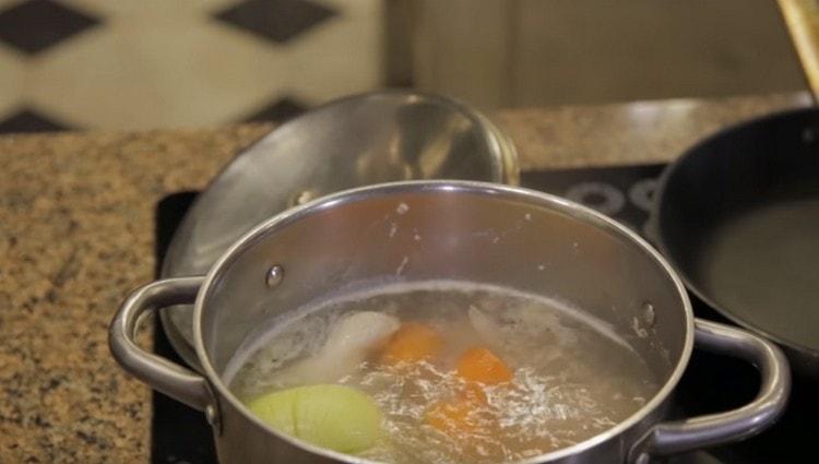 Add carrots and onions to the boiling broth.