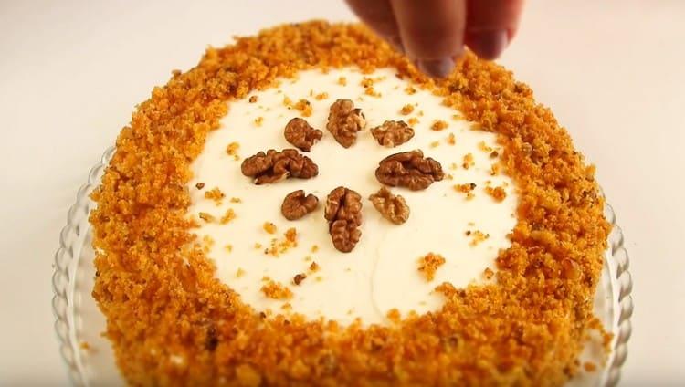Après avoir graissé le dessus et les côtés du gâteau avec la crème, saupoudrer les côtés avec la chapelure, décorer le dessert avec les noix.