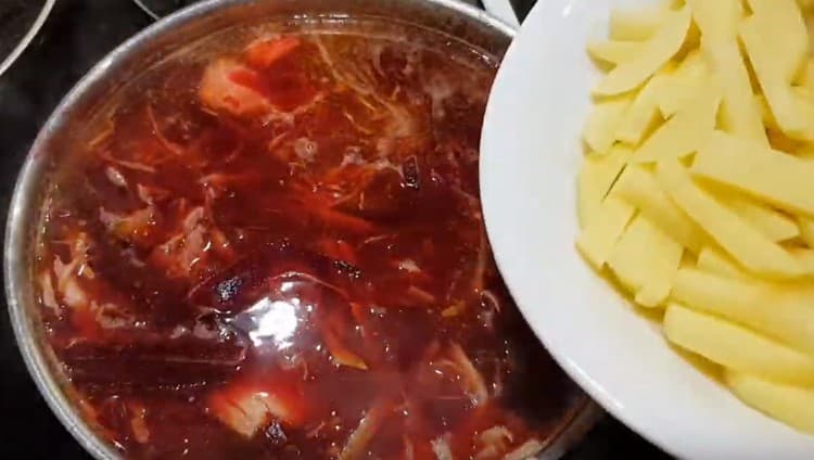 Devolvemos el caldo a la estufa, agregamos carne, frituras, repollo de remolacha y también papas.