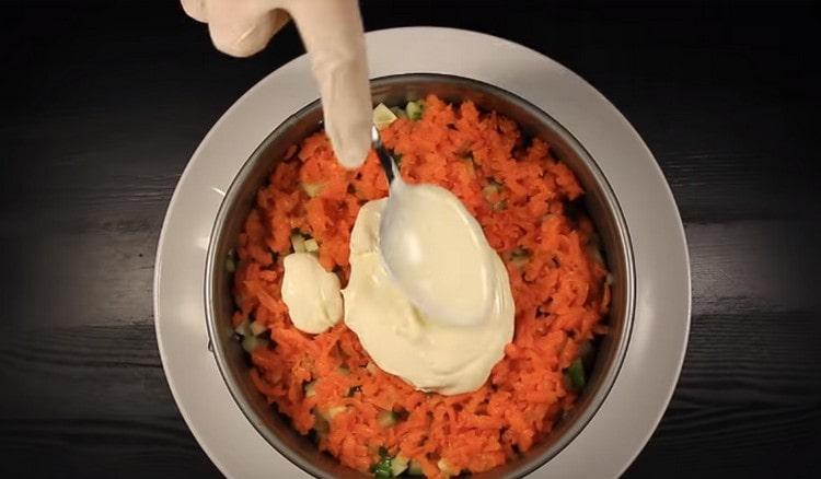Sur le concombre, déposez une couche de carottes râpées et graissez-la de mayonnaise.