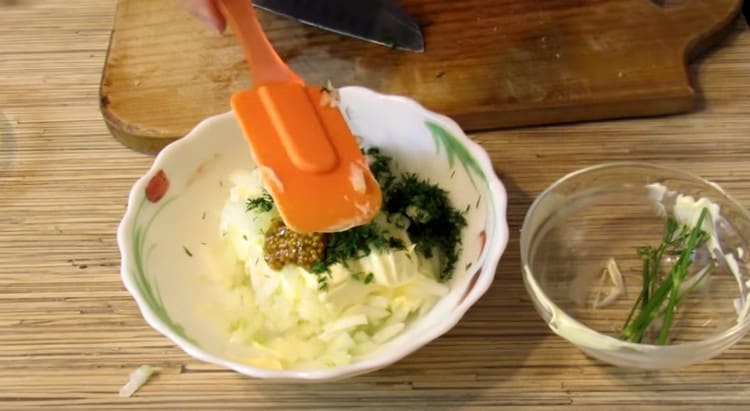 Preparing a sauce of mayonnaise, mustard, chopped onions and dill.