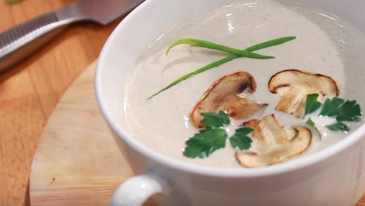Mushroom champignon soup with cream, served, topped with toasted mushroom slices. as well as sprigs of parsley.