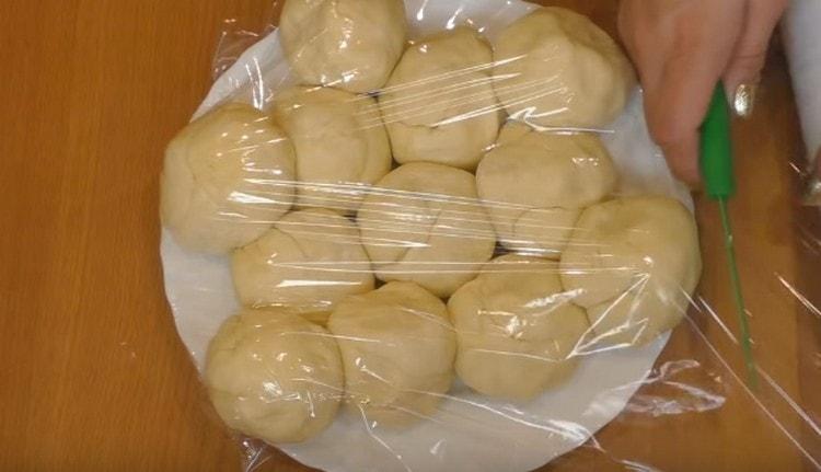 Nous roulons chaque morceau de pâte en une boule, nous les plaçons dans un plat et nous les envoyons au réfrigérateur, en les serrant avec un film plastique.