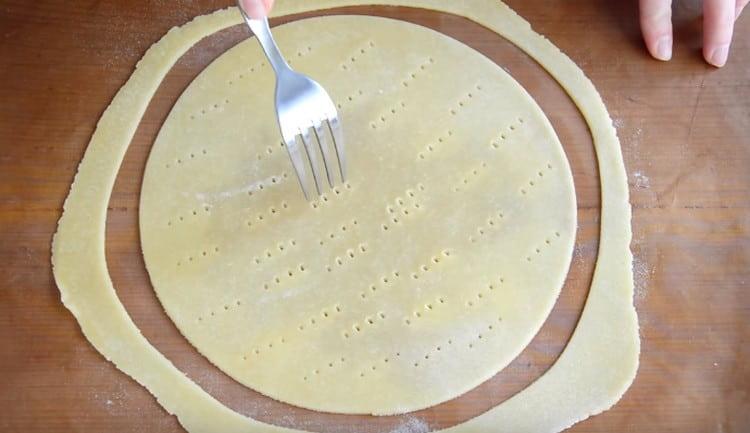 Each roll of dough is thinly rolled out, cut out the cake and prick it with a fork.