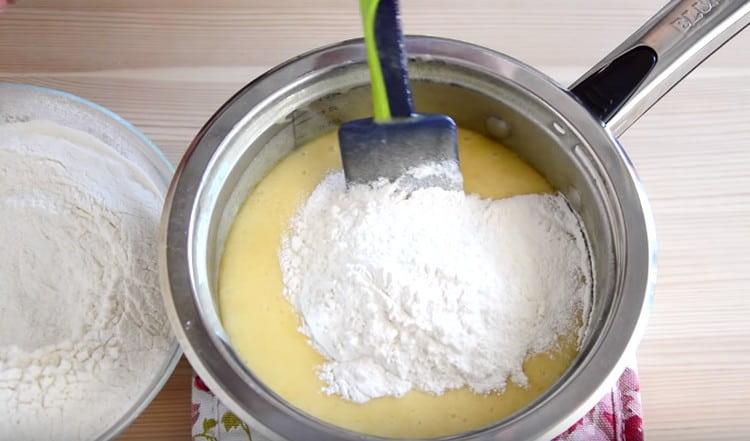 Ajoutez la farine par portions et commencez à pétrir la pâte.