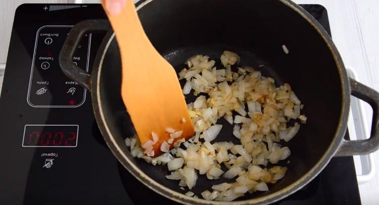 Fry the onion with garlic in a cauldron until golden brown.