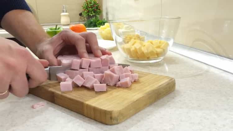 Hacher le jambon pour faire une salade avec du poulet à l'ananas et du maïs