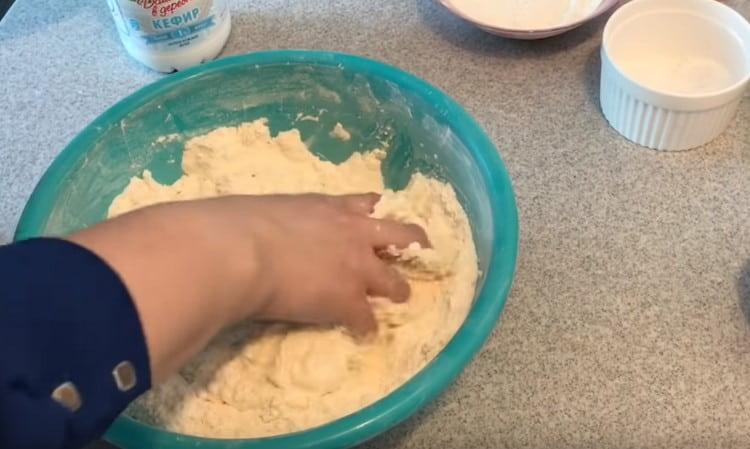 Adding kefir to flour, we begin to knead the dough.