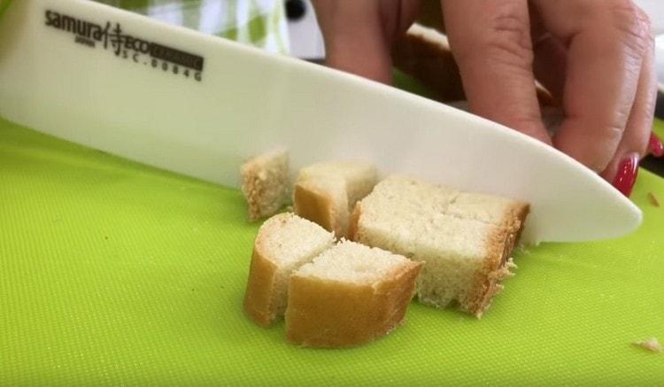 Para preparar los picatostes, corte el pan en un cubo.