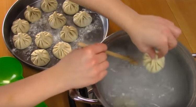 Stirring, lower the khinkali into the crow one at a time.