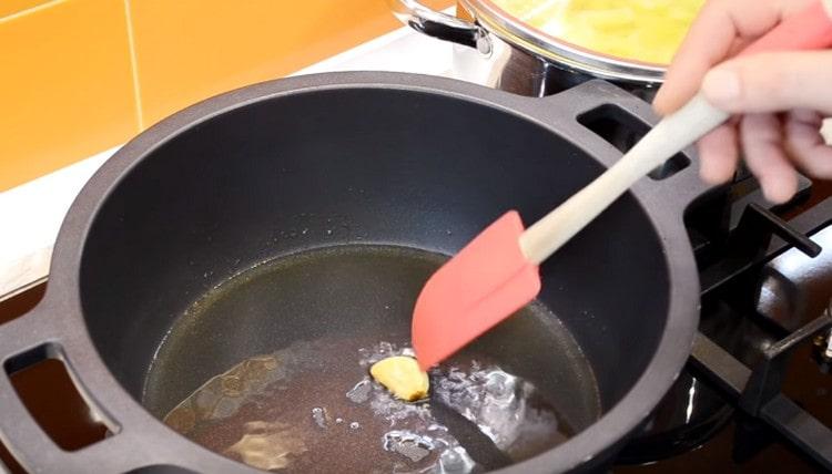 Heat the cauldron or the stewpan, pour the vegetable oil and fry the clove of garlic.