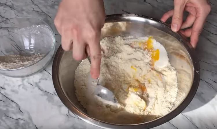 Ajoutez la crème sure et commencez à pétrir la pâte.
