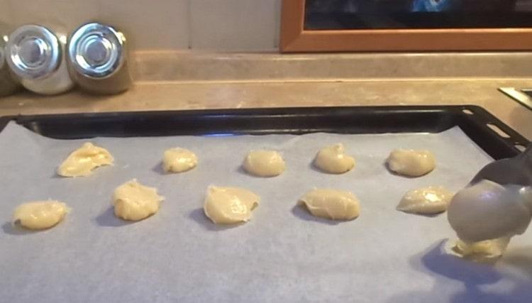 Trempé dans de l'eau avec des cuillères, étendre la pâte sur une plaque à pâtisserie.