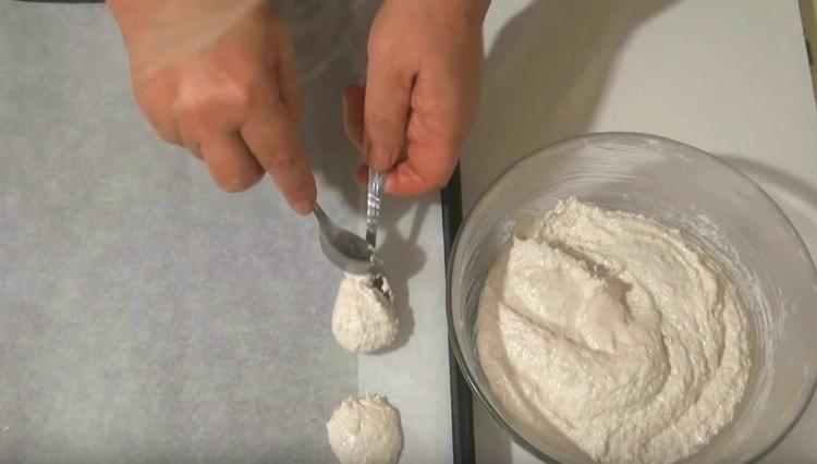 En una bandeja para hornear cubierta con pergamino, extienda la masa de almendras y proteínas con cucharas.