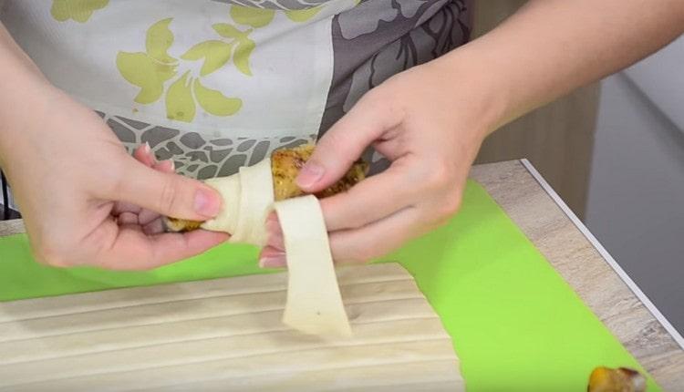 Envelopper doucement chaque pilon de poulet avec une bande de pâte.