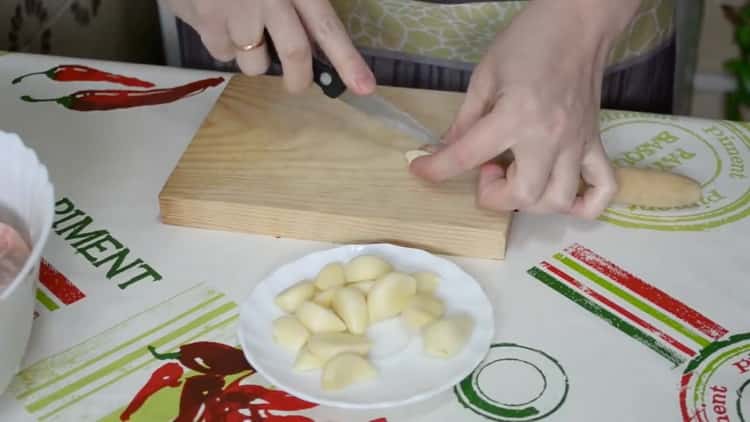 Para cocinar las patas de pollo en el horno, pique el ajo.