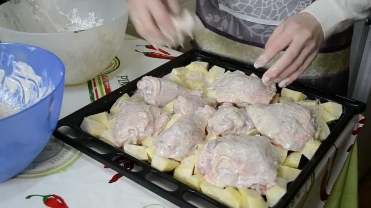 Pour cuire des cuisses de poulet avec des pommes de terre au four, mettez les ingrédients sur une plaque à pâtisserie