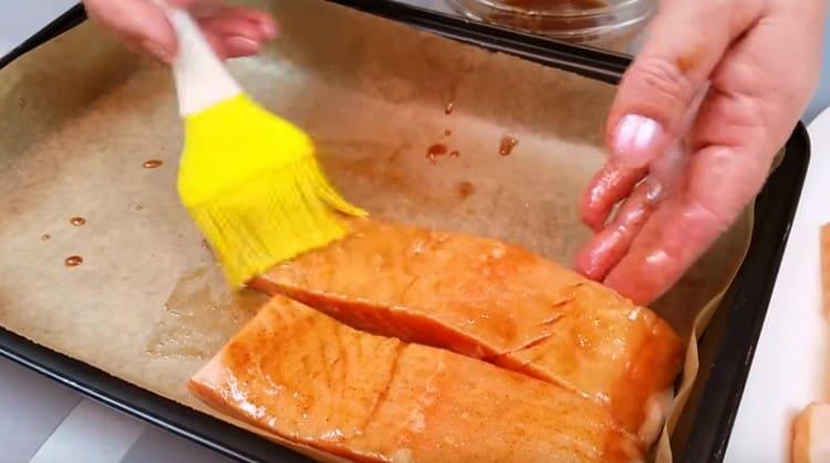 We cover the baking sheet with parchment, grease it with marinade and lay out pieces of salmon, also greasing them with plenty of marinade.