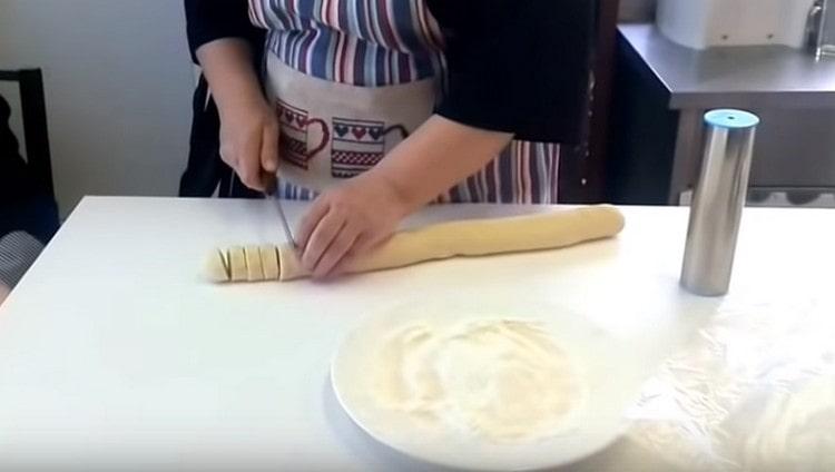 Cut the sausage of dough into portioned billets.