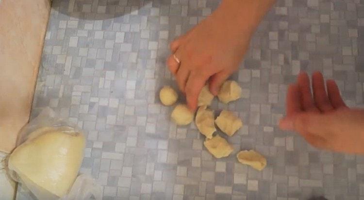 We cut the dough sausage into pieces and roll them into balls.