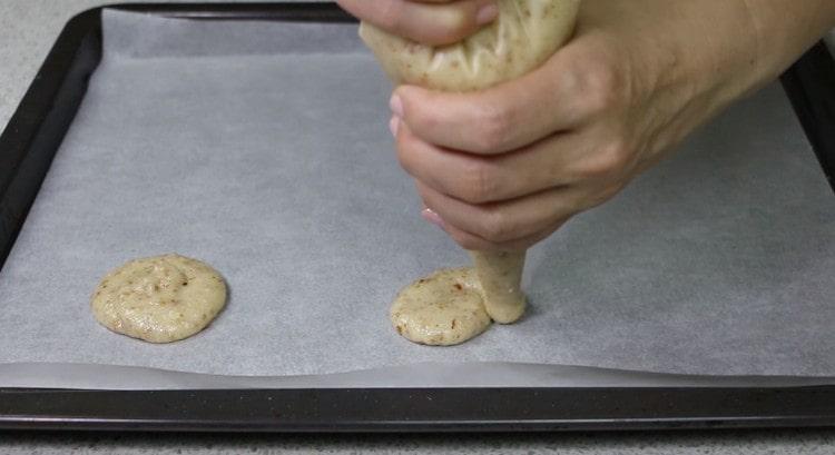 Formamos galletas redondas en una bandeja para hornear cubierta con pergamino.