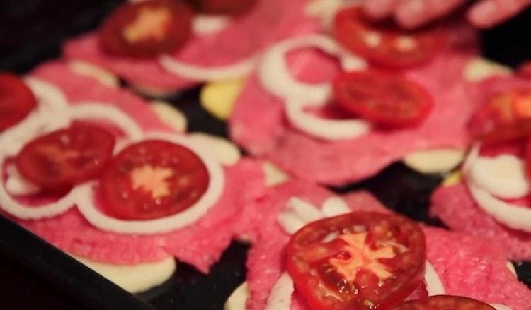narežite rajčicu na krugove i rasporedite ih na meso na vrhu luka.