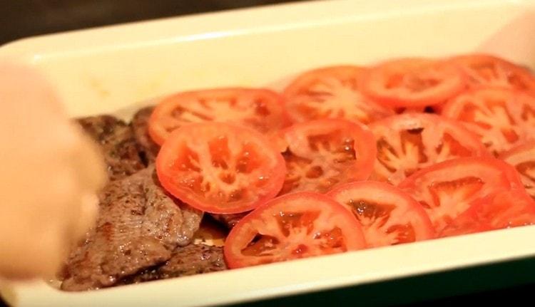 Cover the meat with sliced ​​tomatoes.