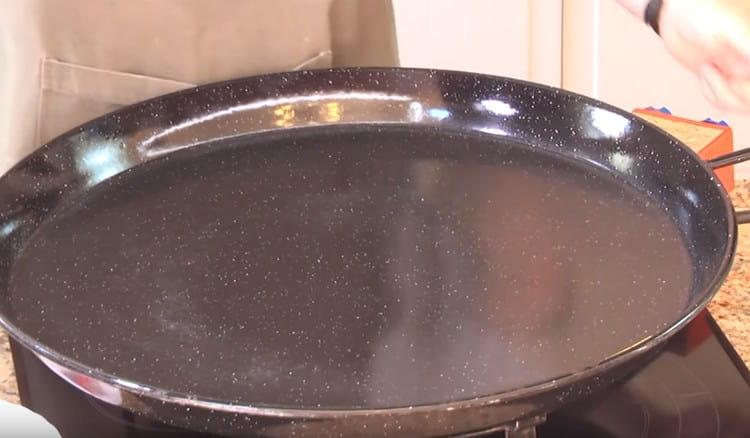 Preheat a special pan for cooking paella.