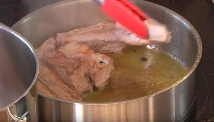 Retirem el pollastre de la cassola i repartim les costelles de porc per fregir-les.