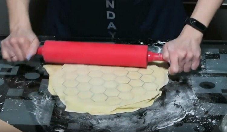 nous recouvrons les boulettes avec les pièces avec une autre couche d’essai laminée et, à l’aide d’un rouleau à pâtisserie, nous pressons les boulettes.