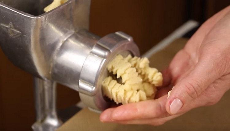 Extendemos un trozo de masa en una picadora de carne y, como resultado, obtenemos galletas rizadas.