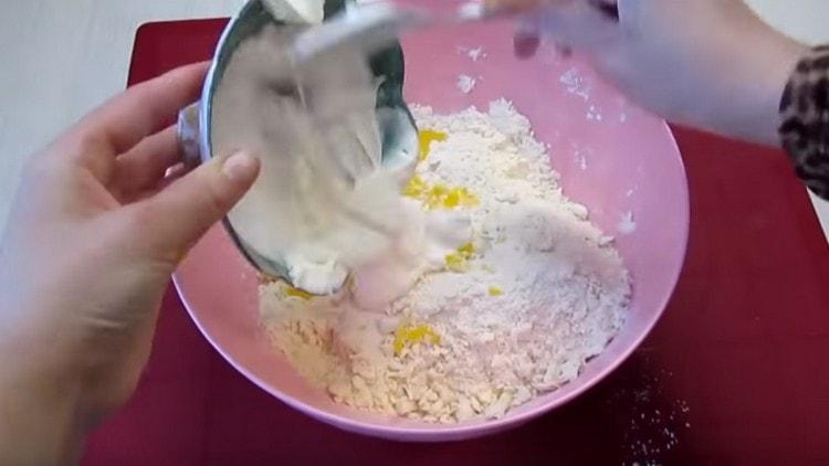 Dans la masse de farine, ajoutez de la crème sure, des jaunes.